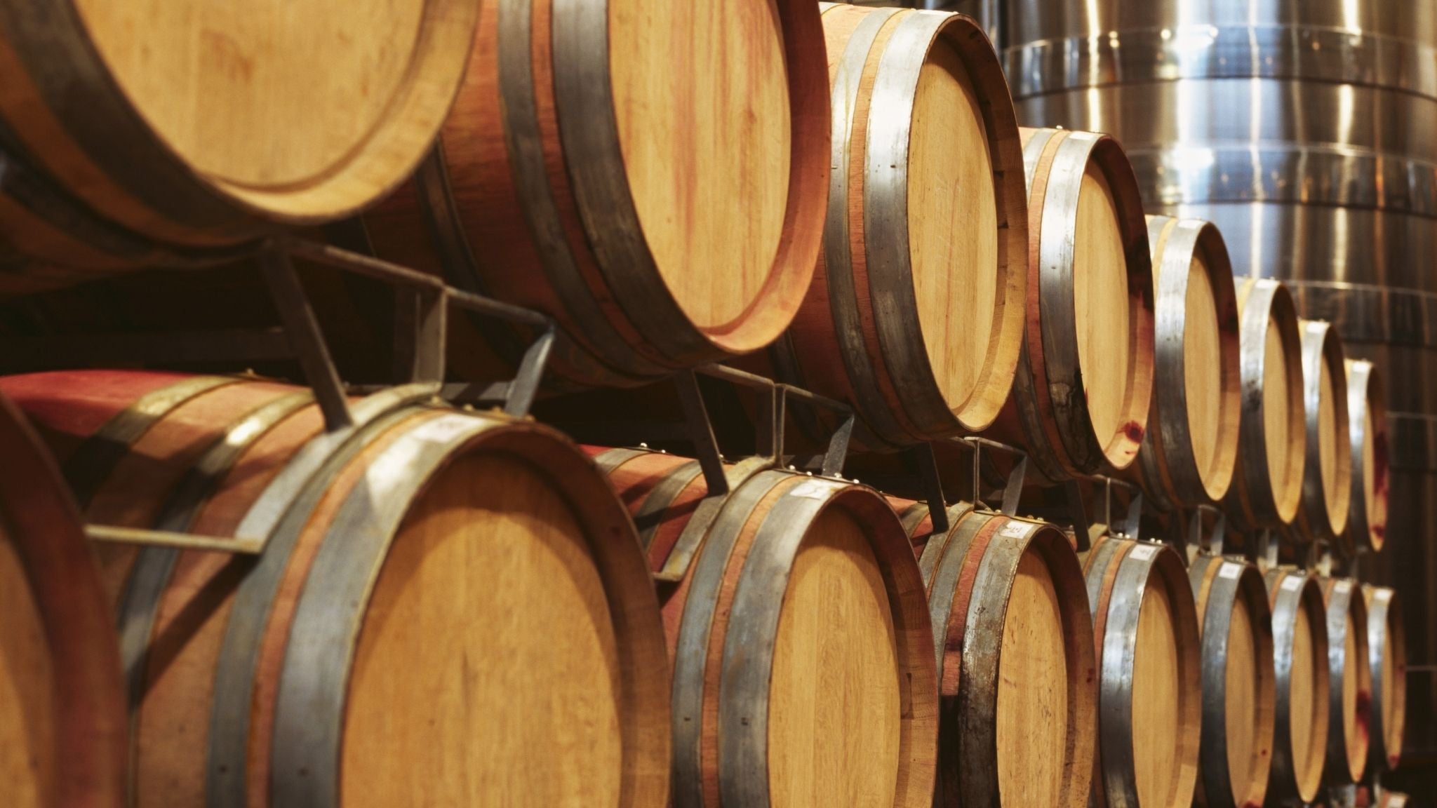 this is an image of wooden wine barrels stacked in a winery cellar for wine aging and storage